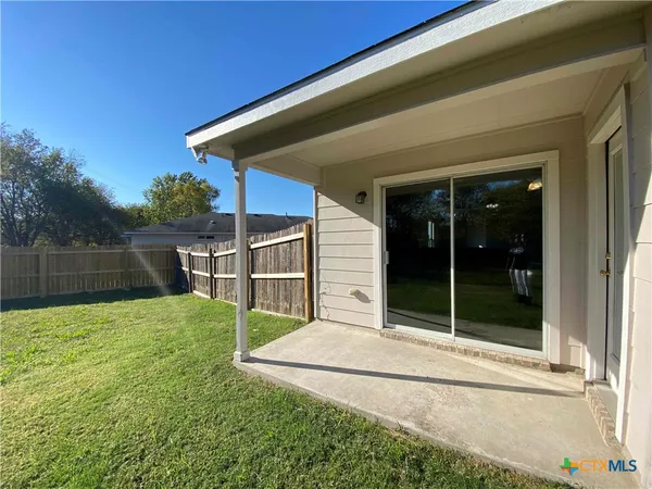 a view of backyard with seating space and wooden fence