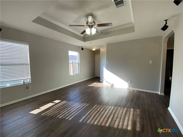 a view of empty room with wooden floor and fan
