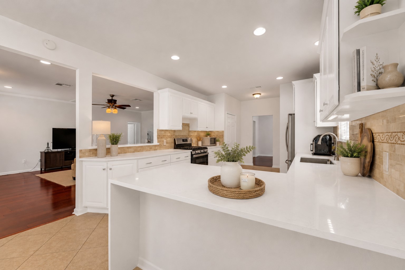 12528 Labrador Cove Austin, TX 78729 - Photo 20 of 40 Virtually Staged – This bright, open-concept kitchen showcases an inviting Pottery Barn-inspired aesthetic with soft neutral décor, warm natural textures, and elegant styling. Crisp white cabinetry, expansive quartz countertops, stainless steel appliances, and generous workspace create the perfect blend of beauty and functionality. The oversized breakfast bar seamlessly connects to the living area, making this kitchen ideal for everyday living, entertaining, and gathering with family and friends. Natural light and thoughtfully curated accents help highlight the spacious layout and timeless design.