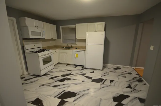 a kitchen with white cabinets and white appliances