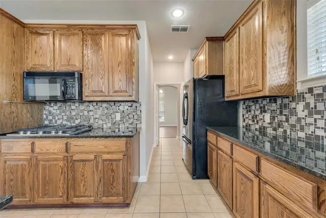 a kitchen with stainless steel appliances granite countertop a refrigerator and a stove top oven