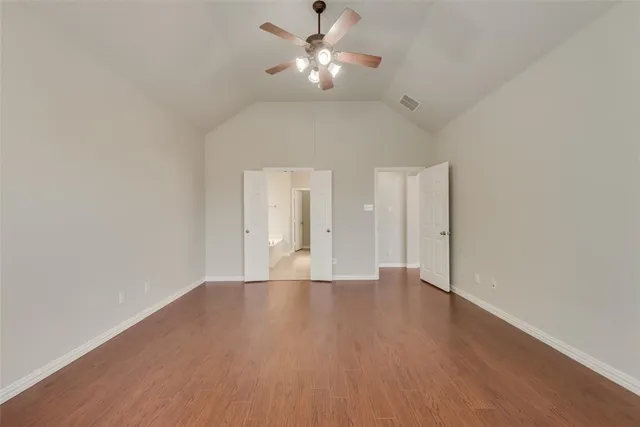 a view of an empty room with chandelier fan and wooden floor