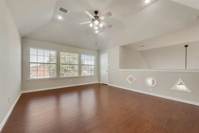 a view of an empty room with a window and wooden floor