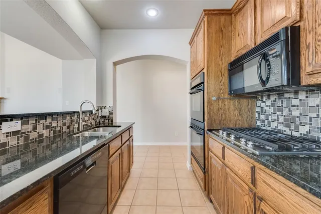 a kitchen with granite countertop a sink stove and cabinets