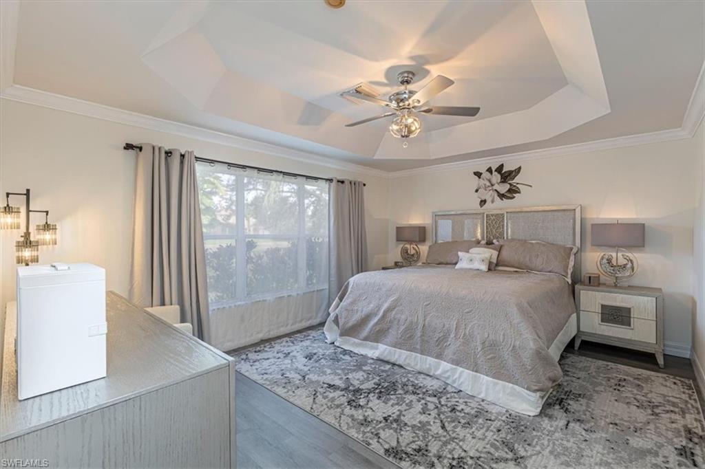 1630 Triangle Palm Terrace Naples, FL 34119 - Photo 13 of 24 a bedroom with a large bed a chandelier and next to a window