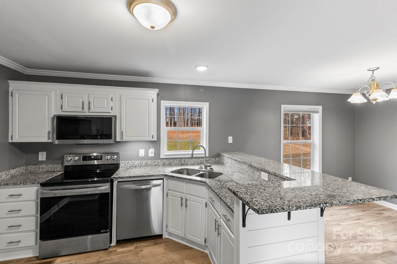 a kitchen with granite countertop a stove sink and microwave