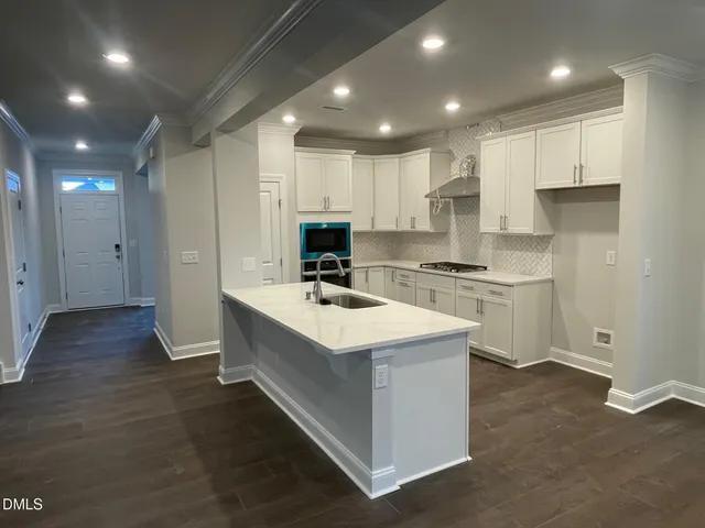 a kitchen that has a lot of white cabinets and stainless steel appliances