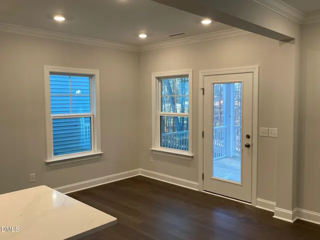 an empty room with wooden floor closet and windows