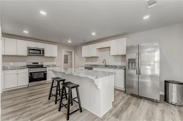 a kitchen with stainless steel appliances granite countertop a refrigerator a stove top oven a sink dishwasher and a refrigerator with wooden floor