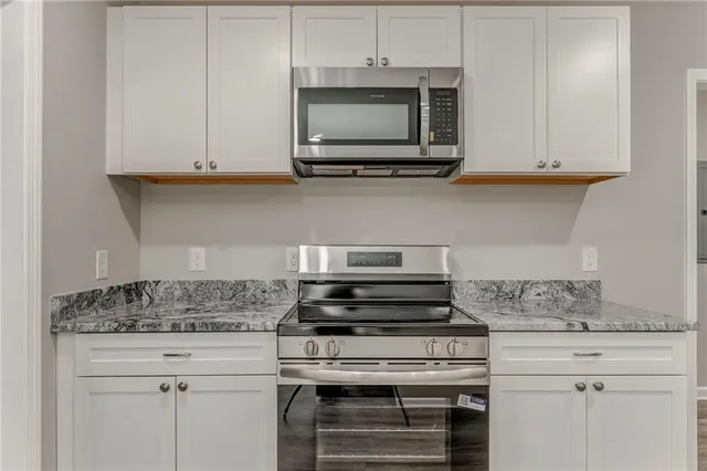 a kitchen with stainless steel appliances granite countertop white cabinets and a stove top oven
