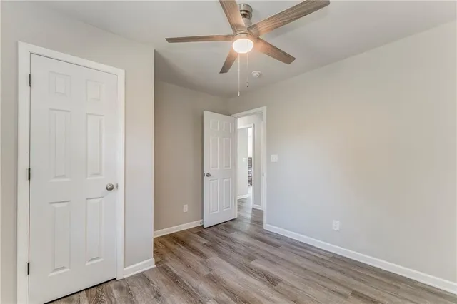an empty room with wooden floor fan and windows