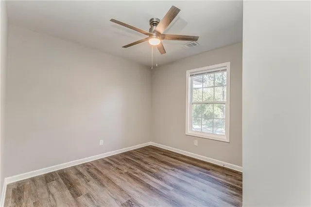 an empty room with wooden floor and windows