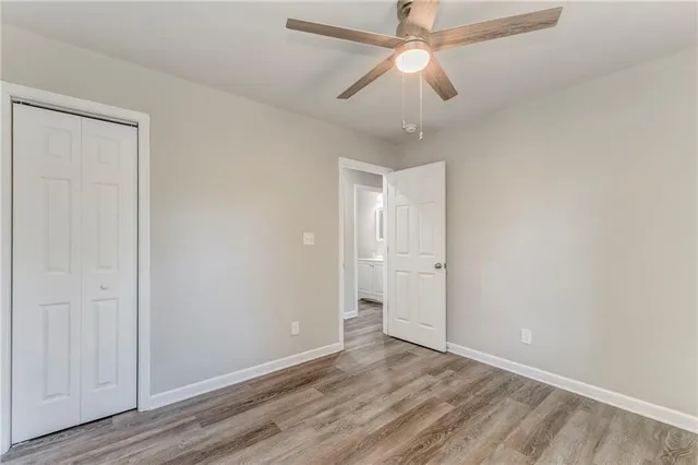 an empty room with wooden floor ceiling fan and windows