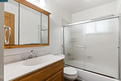 a bathroom with a granite countertop sink toilet and shower