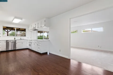 a view of a kitchen with a white cabinets sink and wooden floor