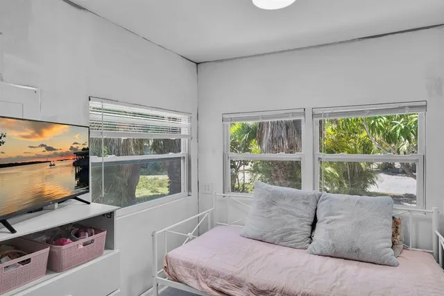 a bedroom with a bed and a flat tv screen next to a window
