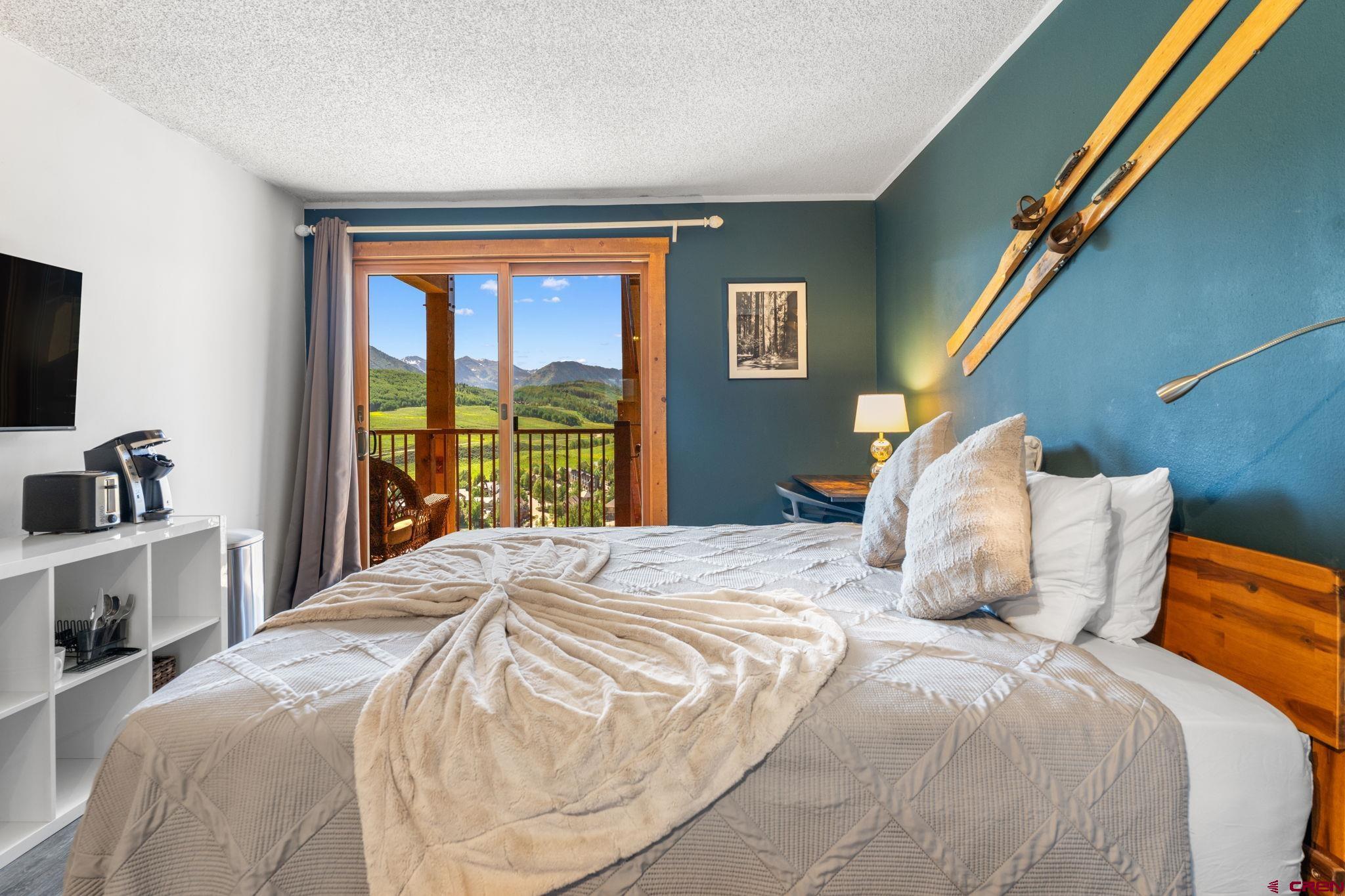 72 Hunter Hill Road, Unit I204 Crested Butte, CO 81225 - Photo 28 of 44 a bedroom with a bed and a flat tv screen next to a window