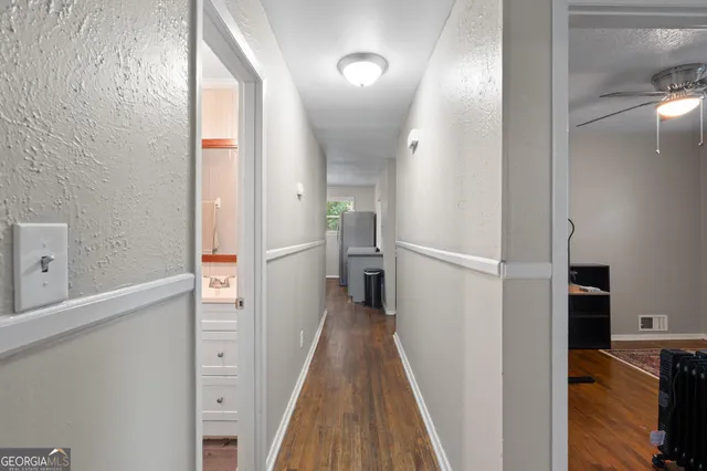a view of a hallway with wooden floor and a bathroom