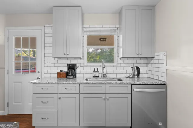a kitchen with white cabinets and a window