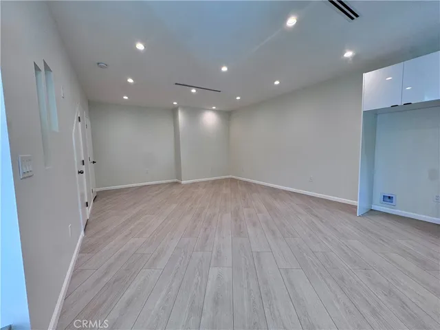 an empty room with wooden floor and entrance