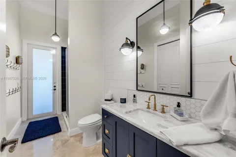 a bathroom with a granite countertop sink a toilet and a large mirror