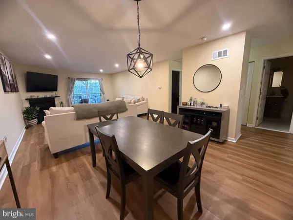a dining room with wooden floor a chandelier a wooden table and chairs