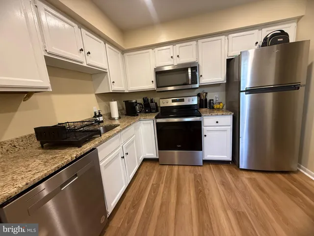 a kitchen with granite countertop a refrigerator stove and sink
