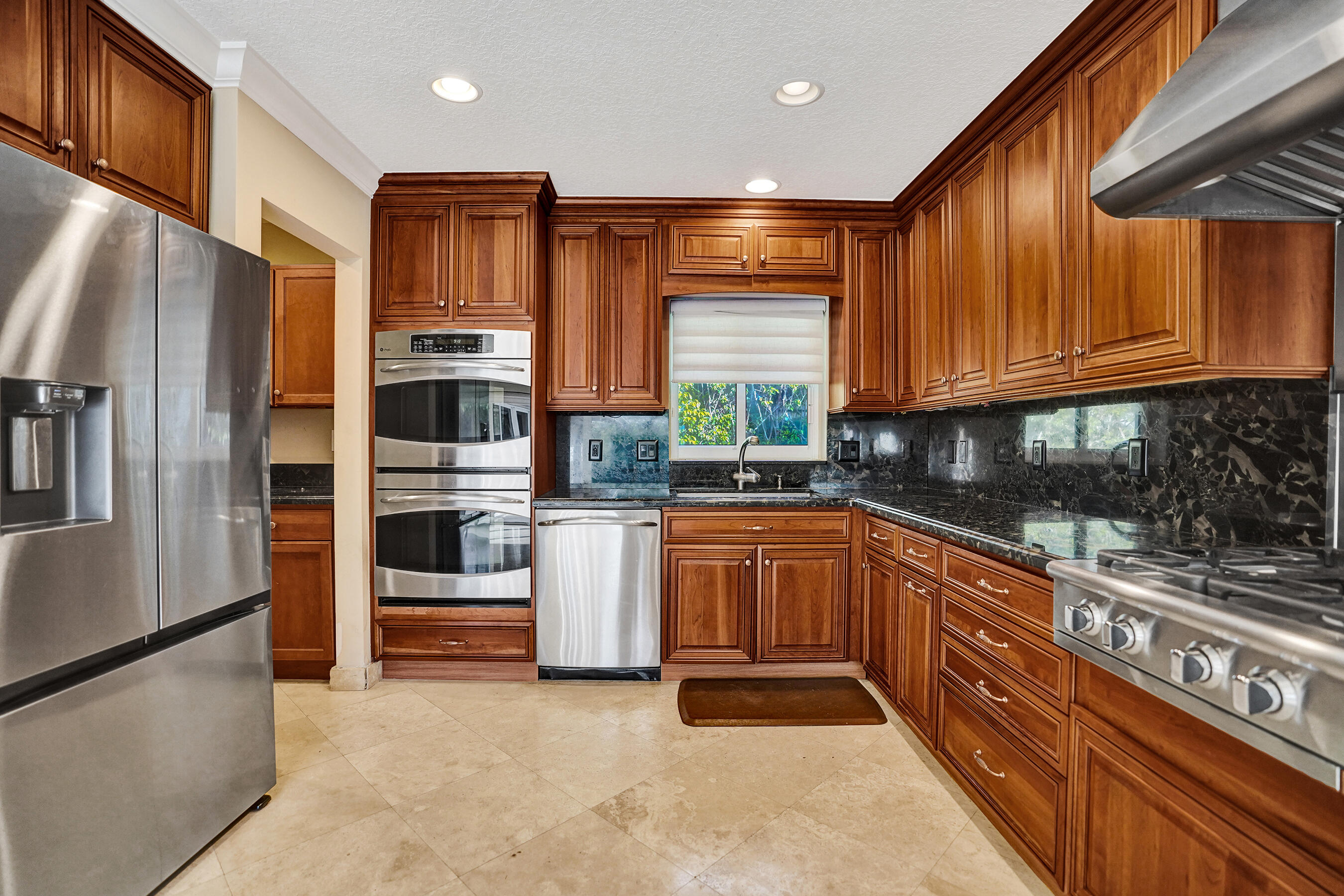 7050 Northeast 7th Avenue Boca Raton, FL 33487 - Photo 11 of 25 a kitchen with stainless steel appliances granite countertop a refrigerator sink and stove