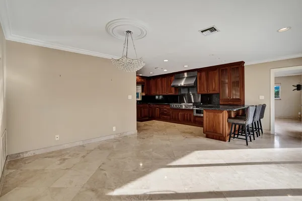 a kitchen with stainless steel appliances granite countertop a stove top oven a sink a dining table and chairs with wooden floor