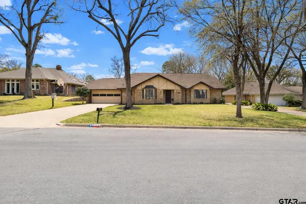 a view of a house with a big yard and large trees