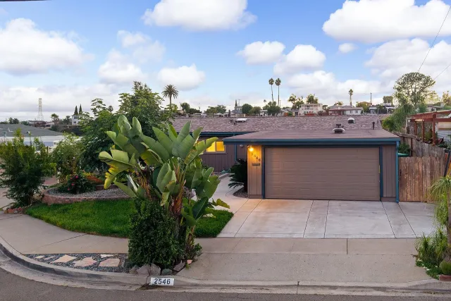 a front view of a house with a yard and potted plants