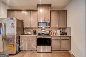 a kitchen with stainless steel appliances granite countertop a stove top oven a sink a dining table and chairs with wooden floor