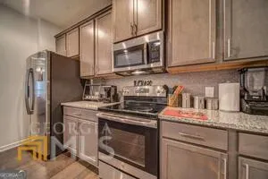 a kitchen with stainless steel appliances granite countertop a refrigerator a stove a sink and a dining table with wooden floor