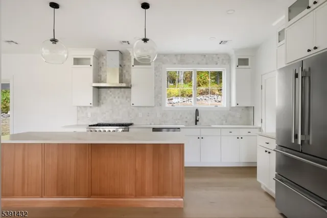 a kitchen with stainless steel appliances granite countertop a refrigerator a sink dishwasher a oven with white cabinets and wooden floor