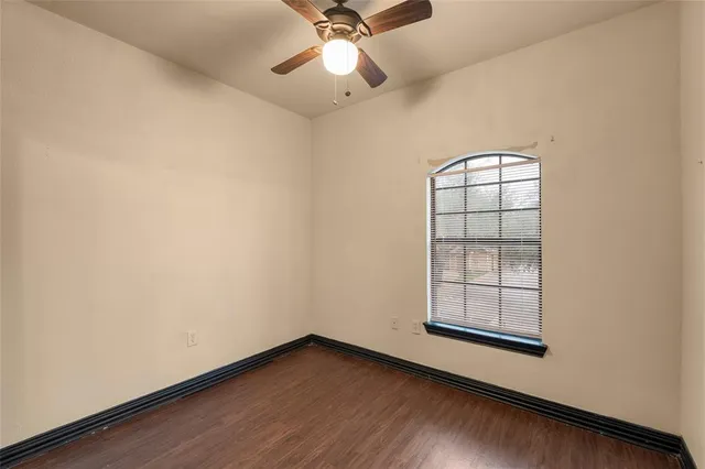 an empty room with windows and ceiling fan