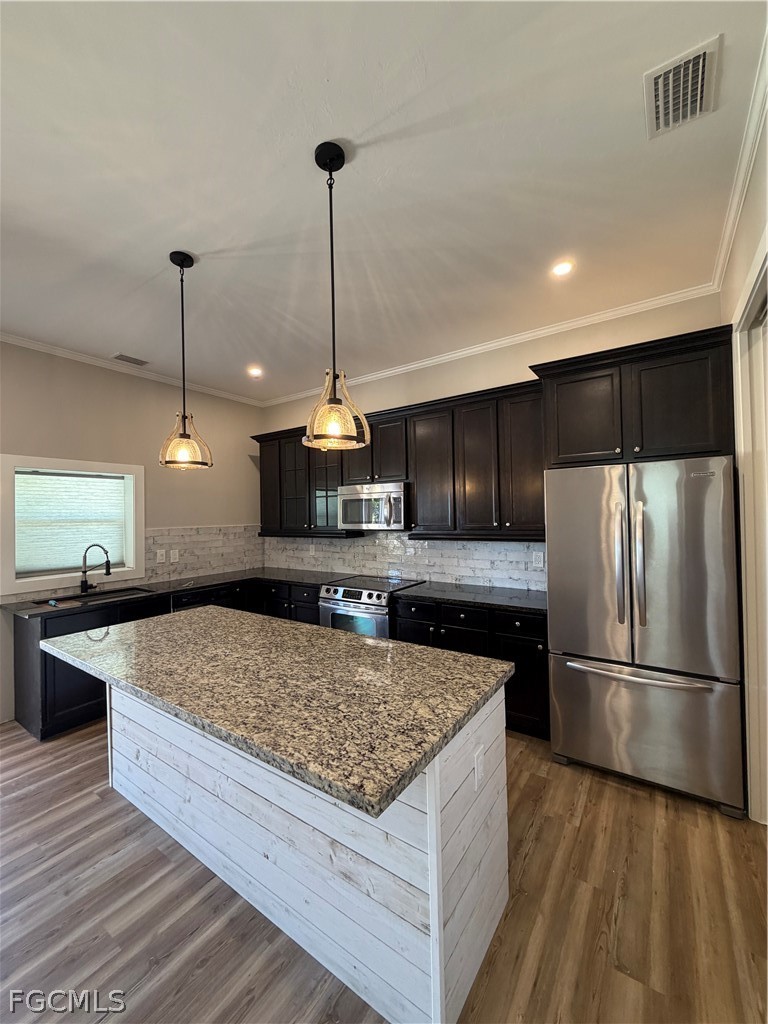 11595 Tomato Road Naples, FL 34114 - Photo 3 of 15 a kitchen with kitchen island a counter top a sink and stainless steel appliances