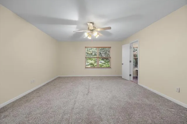 an empty room with a window and a ceiling fan