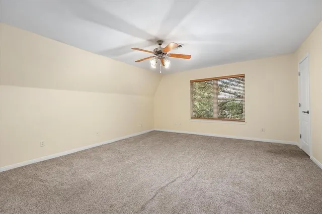 an empty room with a chandelier fan and windows