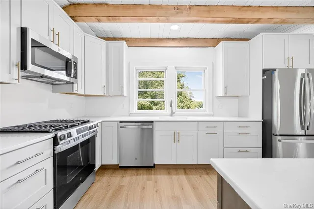 a kitchen with stainless steel appliances white cabinets and a stove top oven