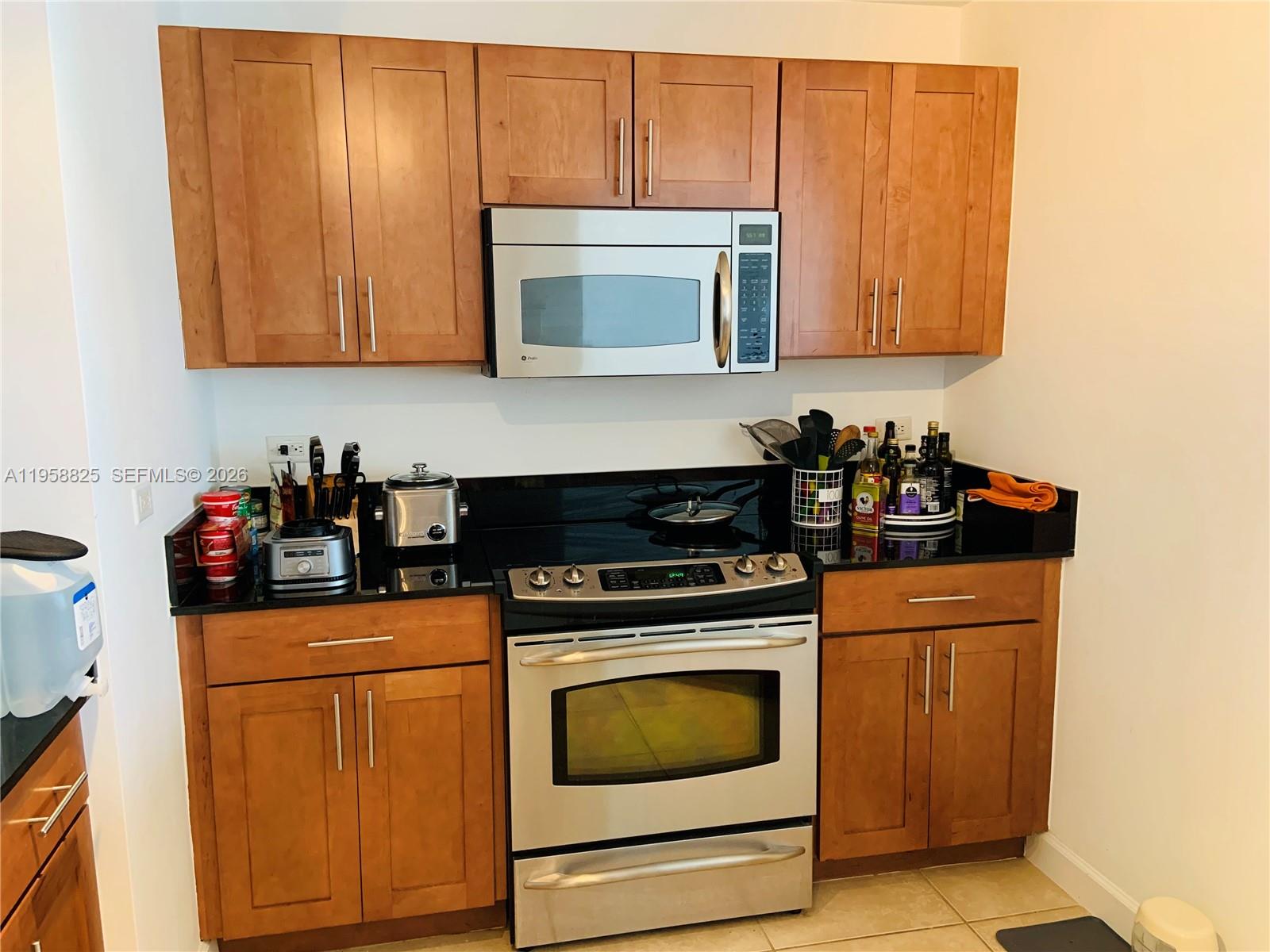 8395 Southwest 73rd Avenue, Unit 704 Miami, FL 33143 - Photo 15 of 47 a kitchen with stainless steel appliances granite countertop a stove a microwave oven and cabinets