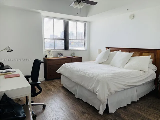 a bedroom with a bed a desk chair and a window