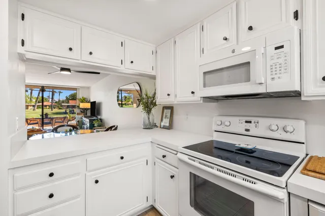 a kitchen with white cabinets and appliances