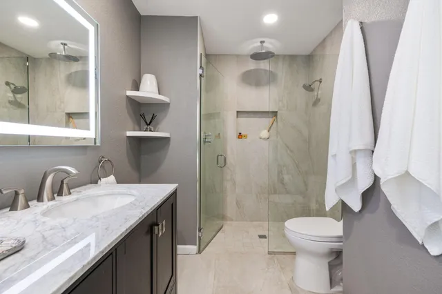 a bathroom with a sink a toilet and shower