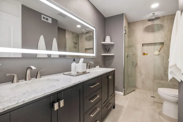 a bathroom with a granite countertop sink a toilet and shower
