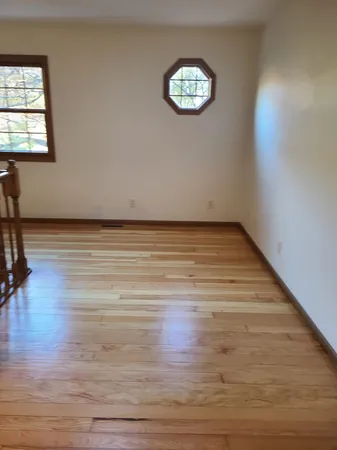 a view of an empty room with wooden floor and a window