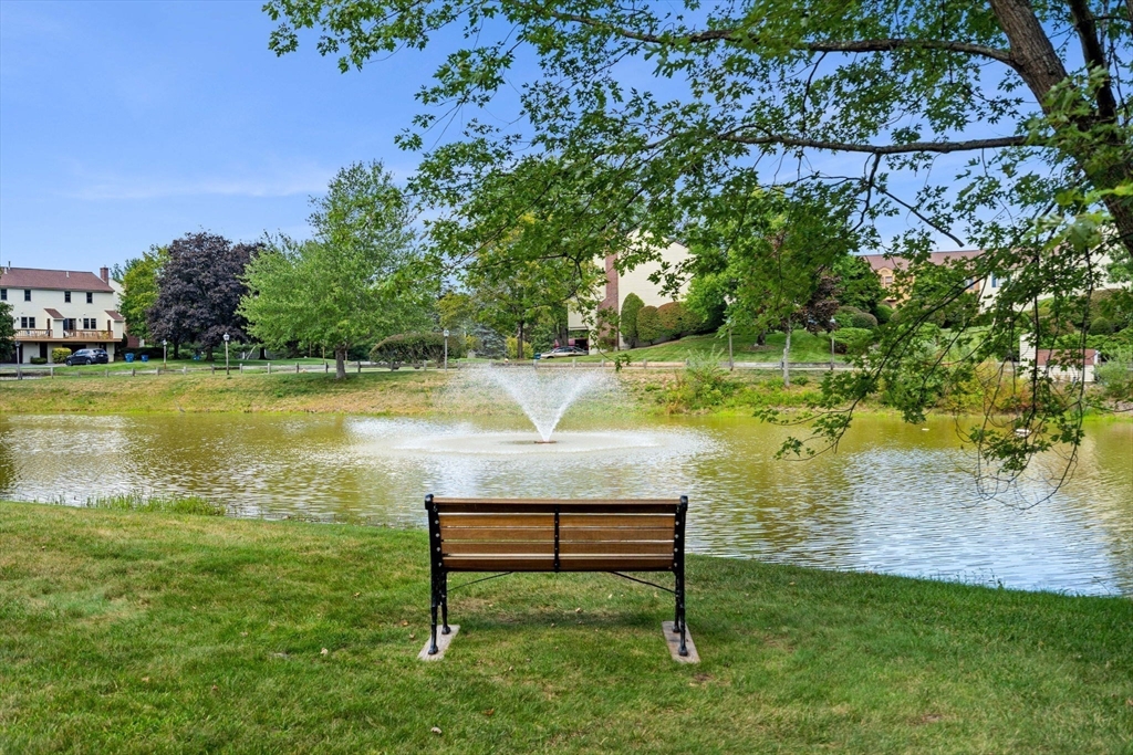 290 Apache Way, Unit 290 Tewksbury, MA 01876 - Photo 26 of 29 a view of a lake with a bench and trees in the background