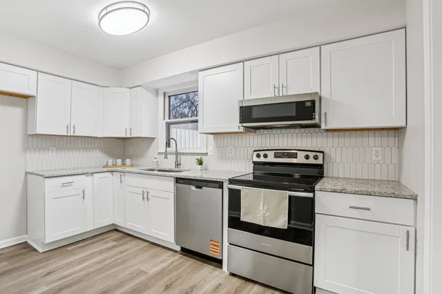 a kitchen with granite countertop a sink a stove and cabinets