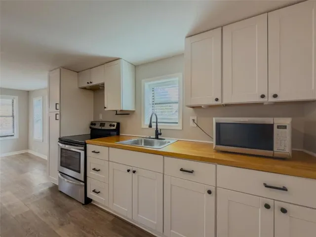 a kitchen with stainless steel appliances granite countertop a sink a stove and white cabinets