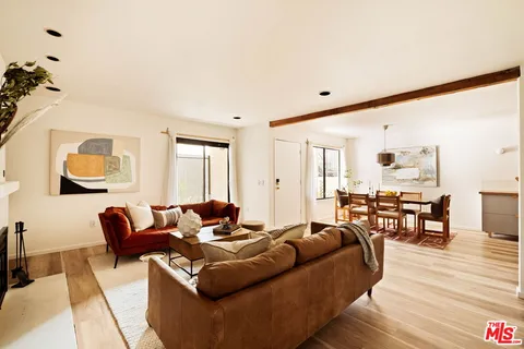 a living room with furniture kitchen view and a wooden floor