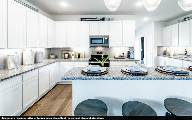 a kitchen with stainless steel appliances granite countertop a sink a stove a microwave a refrigerator and cabinets